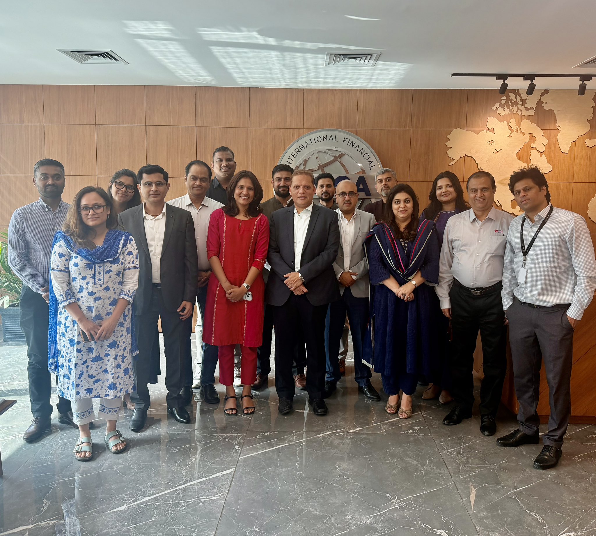 Group photo at the GIFT International Fintech Institute: SPF founders and senior IFSCA officials standing together in front of the IFSCA world-map mural