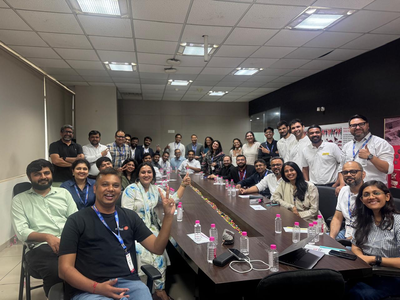 Group photo at the Startup RoundTable at GATE 2026 in Ahmedabad: 30+ founders around a long conference table, with eChai's host in the foreground and the GCCI room behind them